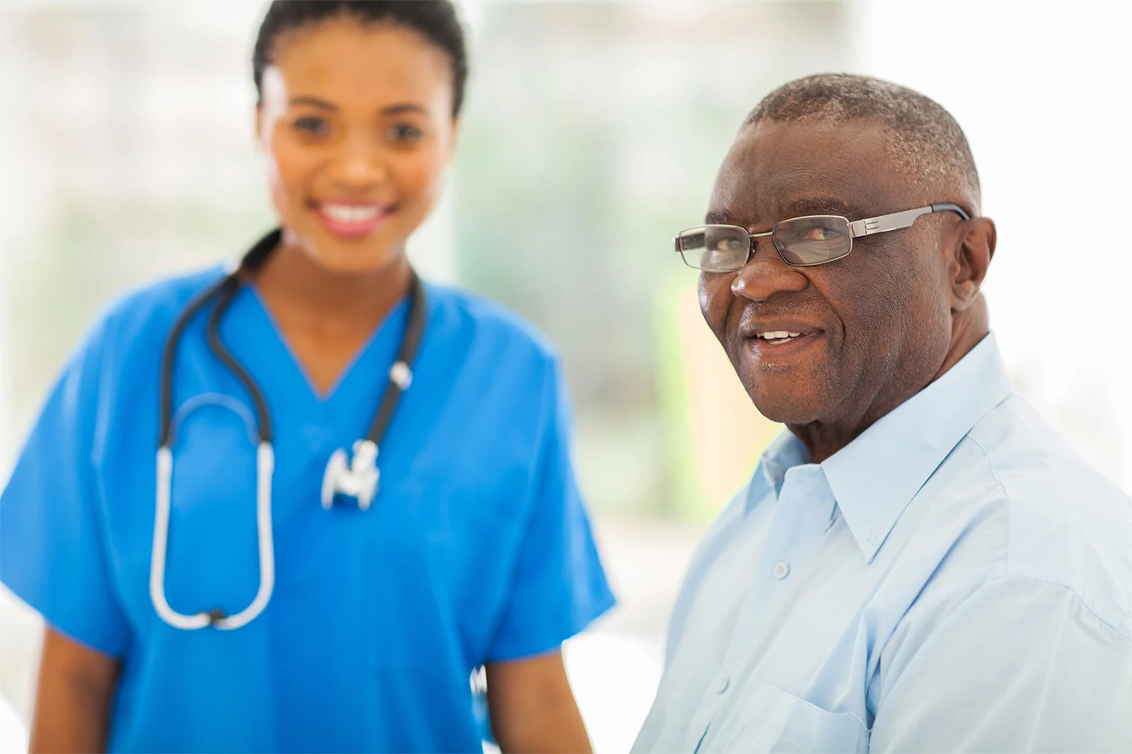 Older black man patient with nurse smiling